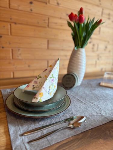 a table with three plates and a vase of flowers at moderne Apartments am Attersee Dachsteinblick - ruhige Lage mit traumhaften Blick in Nussdorf am Attersee