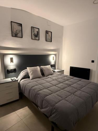 a bedroom with a large bed and two pictures on the wall at Caleros 8 - Apartamento 2 in Cáceres