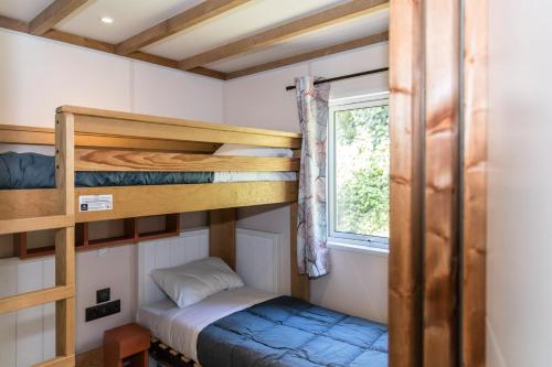 a small bedroom with bunk beds and a window at Camping La Vallée in Houlgate
