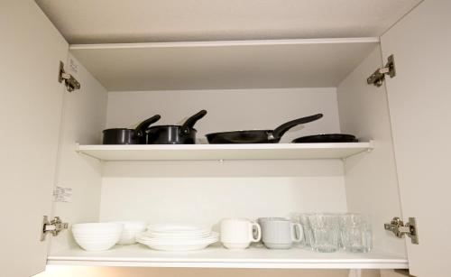 a shelf with cups and utensils in a kitchen at 銀座線すぐ近く 歴史寺院巡りに最適 松が谷の静かな一軒家 Sio1g in Tokyo