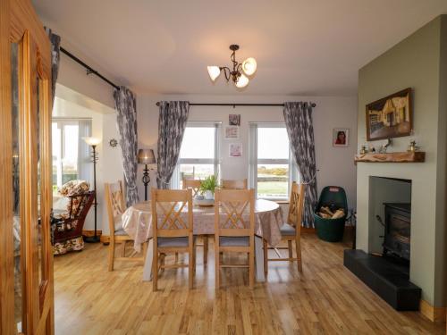 a dining room with a table and chairs and a fireplace at Radharc Na Tra in Burtonport