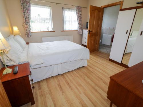 a bedroom with a white bed and a wooden floor at Radharc Na Tra in Burtonport
