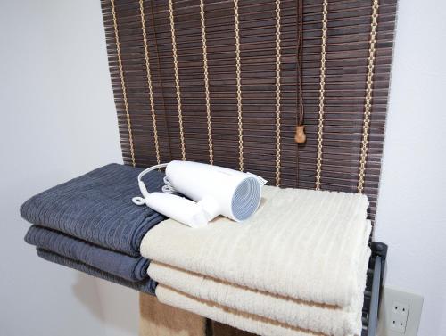 a telephone sitting on a pile of towels on a bed at 銀座線すぐ近く 歴史寺院巡りに最適 松が谷の静かな一軒家 Sio1g in Tokyo