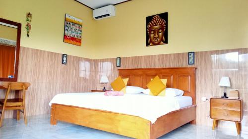 - une chambre dotée d'un grand lit avec un masque mural dans l'établissement Alamku Bungalow, à Tirtagangga