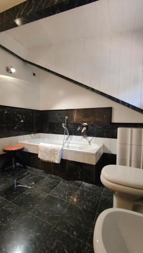 a bathroom with a tub and a toilet and a sink at Scarlet Flower - Lago Maggiore in Meina