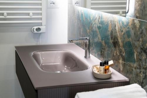 a white sink in a bathroom with a tile wall at Pietra Viva Suite e Relax in Veglie