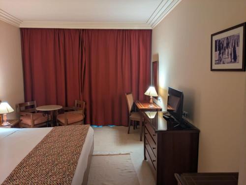 a hotel room with a bed and a red curtain at Hôtel LE CONSUL in Tunis