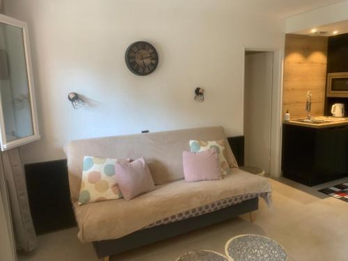 a living room with a couch and a clock on the wall at Appartement Coté jardin in Saint-Raphaël