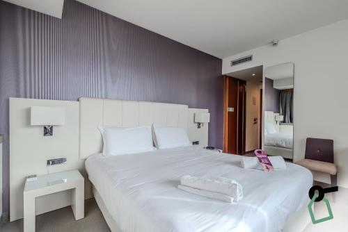a bedroom with a large white bed and a chair at HOTIDAY Room Collection - Trapani in Trapani