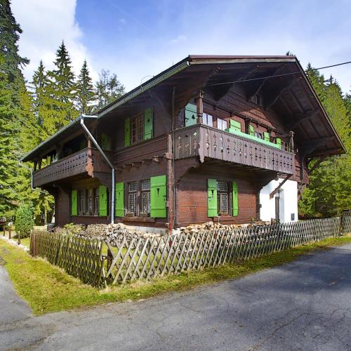 a wooden house with green doors and a fence at Apartment Chalet Kladska in Mariánské Lázně