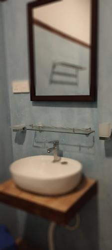 a white bathroom sink with a mirror and a mirrorounter sidx sidx sidx at Rolling Waves Midigama East in Midigama