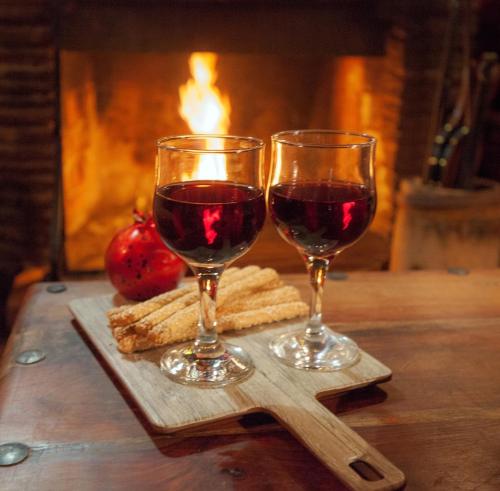 two glasses of red wine on a wooden cutting board at Dandy Villas Agoriani-Chalet Orelia-Fireplace in Eptalofos