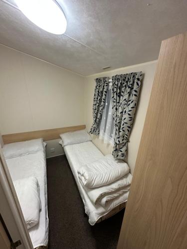 a small room with two beds and a window at Sunnymede E11 Keyshare Holiday lets 8 Berth in Skegness