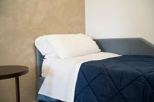a bed with a blue and white blanket and a table at Pietra Viva Suite e Relax in Veglie