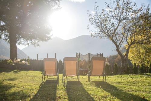 three chairs sitting in the grass in a field at Apartments Hochbrunn - Pension Brunner in San Giuseppe in Anterselva