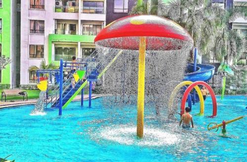 a child playing in a fountain in a swimming pool at Ipoh Waterpark Manhattan Premium Suites by IWH Suites in Ipoh