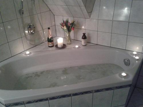 a bath tub with two bottles of wine and candles at RügenHerz DACHTRÄUME Atelierwohnung 1 - 4 Personen in Parchtitz