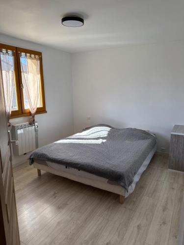 une chambre avec un lit dans une pièce blanche dans l'établissement T2 meublé 42m2 avec terasse, à Le Monastère