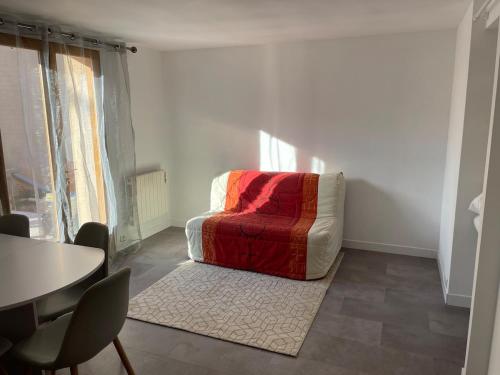 un salon avec une chaise rouge et une table dans l'établissement T2 meublé 42m2 avec terasse, à Le Monastère