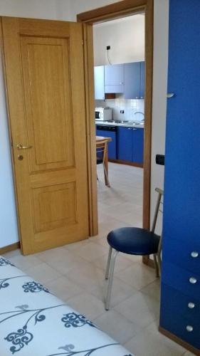 a room with a door and a chair and a kitchen at Riviera Residence in Marina di Pietrasanta