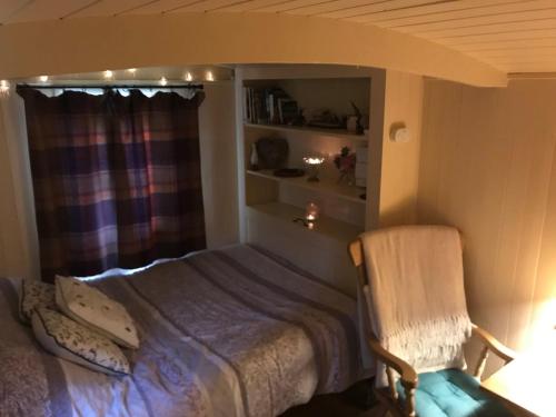 a bedroom with a bed and a chair and a window at Phoenix Farm Shepherds Hut,Minions, Cornwall in Liskeard