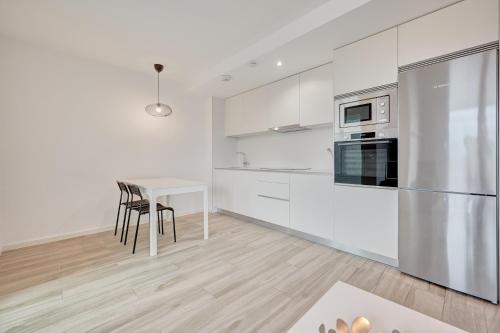 a white kitchen with a table and a refrigerator at Ripa by Clabao in Burlada