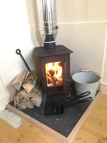 a wood stove in a room with a fire at Phoenix Farm Shepherds Hut,Minions, Cornwall in Liskeard