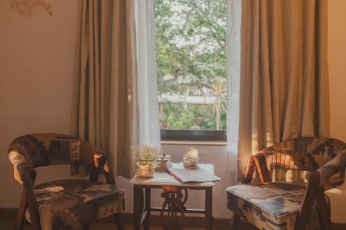 a living room with two chairs and a table and a window at Brij Paraiso Saligao, Goa - An Indo-Portuguese Villa in Calangute