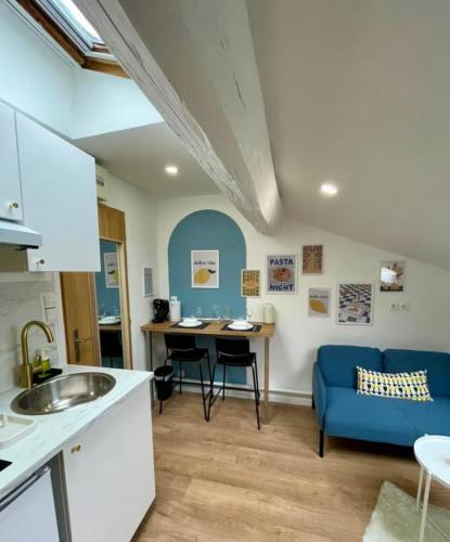Il comprend une cuisine et un salon doté d'un canapé bleu. dans l'établissement Le Petit Rome Proche gare, à Lyon