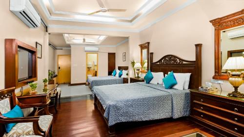 a hotel room with two beds and a table at Hotel Ajanta - Colonial Charm Award Winning Luxury Hotel in the Heart of the City in New Delhi