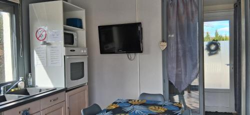 a kitchen with a table and a tv on the wall at Studio au bord de l'étang in Laives