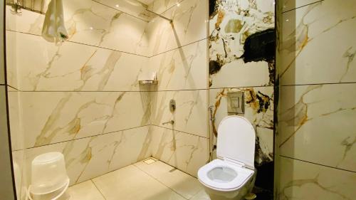 a bathroom with a white toilet and a marble wall at Shree Anantay Club & Resort in Ujjain