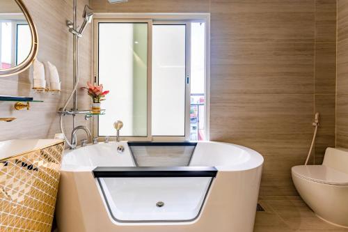 a bathroom with a tub and a toilet and a sink at Mai Hotel in Hanoi