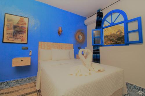 a blue bedroom with a bed with a swan on it at CASA TROUSSI in Chefchaouene