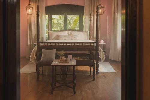 a bedroom with a bed with a table in front of it at Brij Paraiso Saligao, Goa - An Indo-Portuguese Villa in Calangute