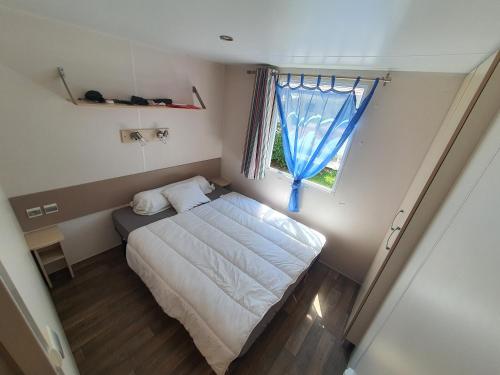 a small bedroom with a bed and a window at Mobil-home 3 chambres climatisé sur le domaine 4 étoiles Rivages des Landes in Aureilhan