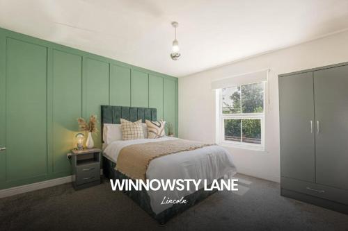 a bedroom with a bed with green walls and a window at Cosy and Lovely 3-bed Home in Lincoln by Renzo, Free Wi-Fi, Sleeps 8! in Lincolnshire