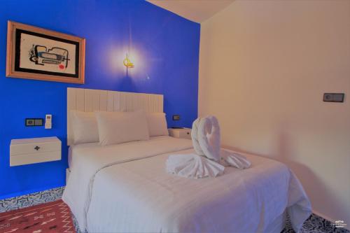 a bedroom with a white bed with blue walls at CASA TROUSSI in Chefchaouene