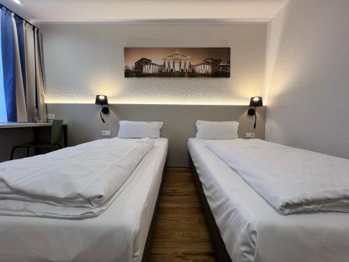 two beds in a room with a picture on the wall at Plaza Inn Berlin Süd Ludwigsfelde in Ludwigsfelde