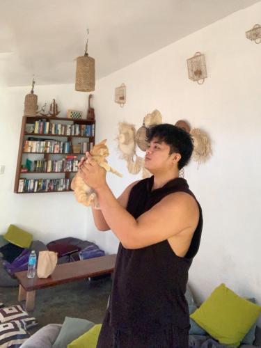 a man holding a cat in a living room at Jaydy hostel in General Luna