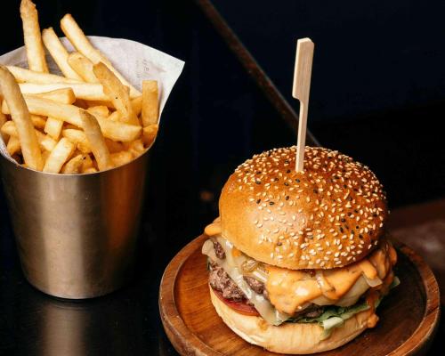 a hamburger and french fries on a wooden plate at Hyatt Regency London Albert Embankment in London