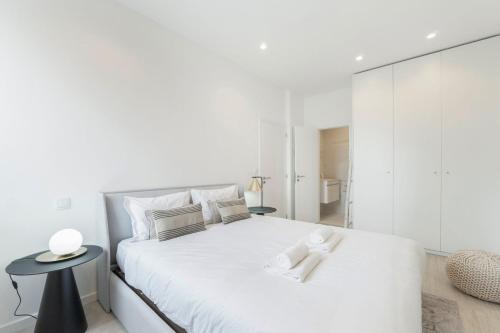 a white bedroom with a white bed and a side table at GuestReady - Good times in Matosinhos in Matosinhos