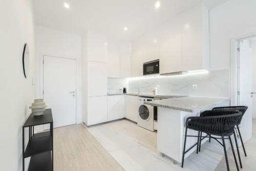 a white kitchen with black chairs and a counter at GuestReady - Good times in Matosinhos in Matosinhos