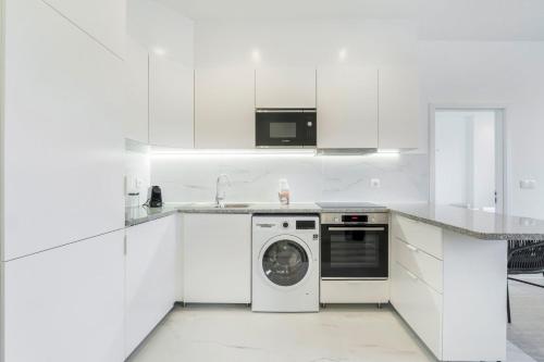 a white kitchen with a washing machine in it at GuestReady - Good times in Matosinhos in Matosinhos