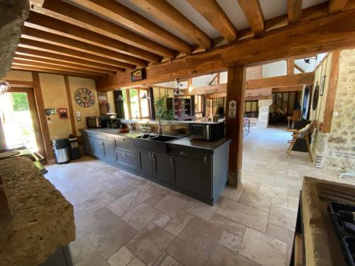 a large kitchen with wooden ceilings and a stone floor at Gîte Normand 26 couchages in Rai-sur-Rîle
