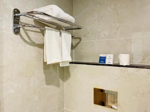 a bathroom with a shower with white towels on a shelf at Sobit Sarovar Portico in Palolem
