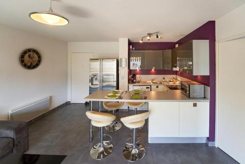 une cuisine avec des placards blancs et un îlot avec des tabourets de bar dans l'établissement Les Vergers - Calme, Piscine, Parking & Terrasse, à La Valette-du-Var