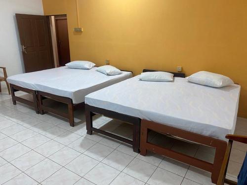 two beds sitting next to each other in a room at Thinakkural Rest in Jaffna