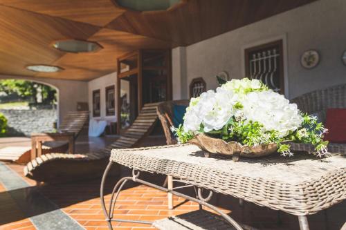 a wicker table with a bouquet of white flowers on it at Luce del lago in Moltrasio