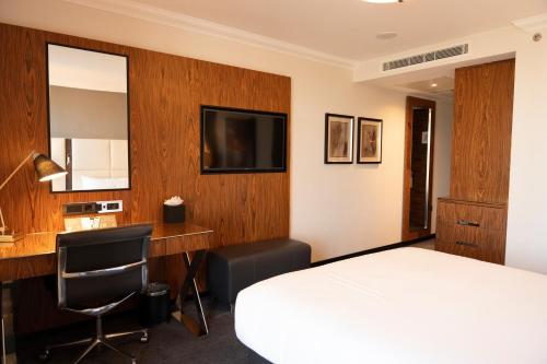 a hotel room with a bed and a desk and a television at Hyatt Regency London Albert Embankment in London